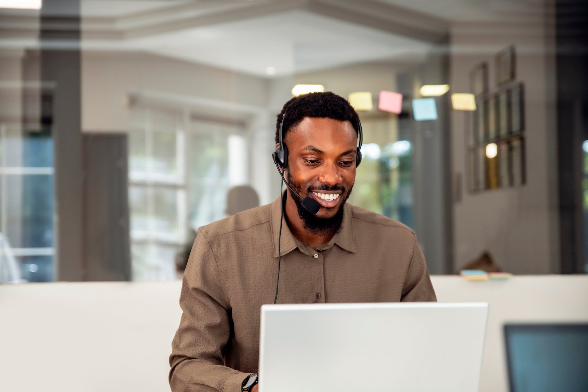 Call center employee on laptop, smiling while talking to customer