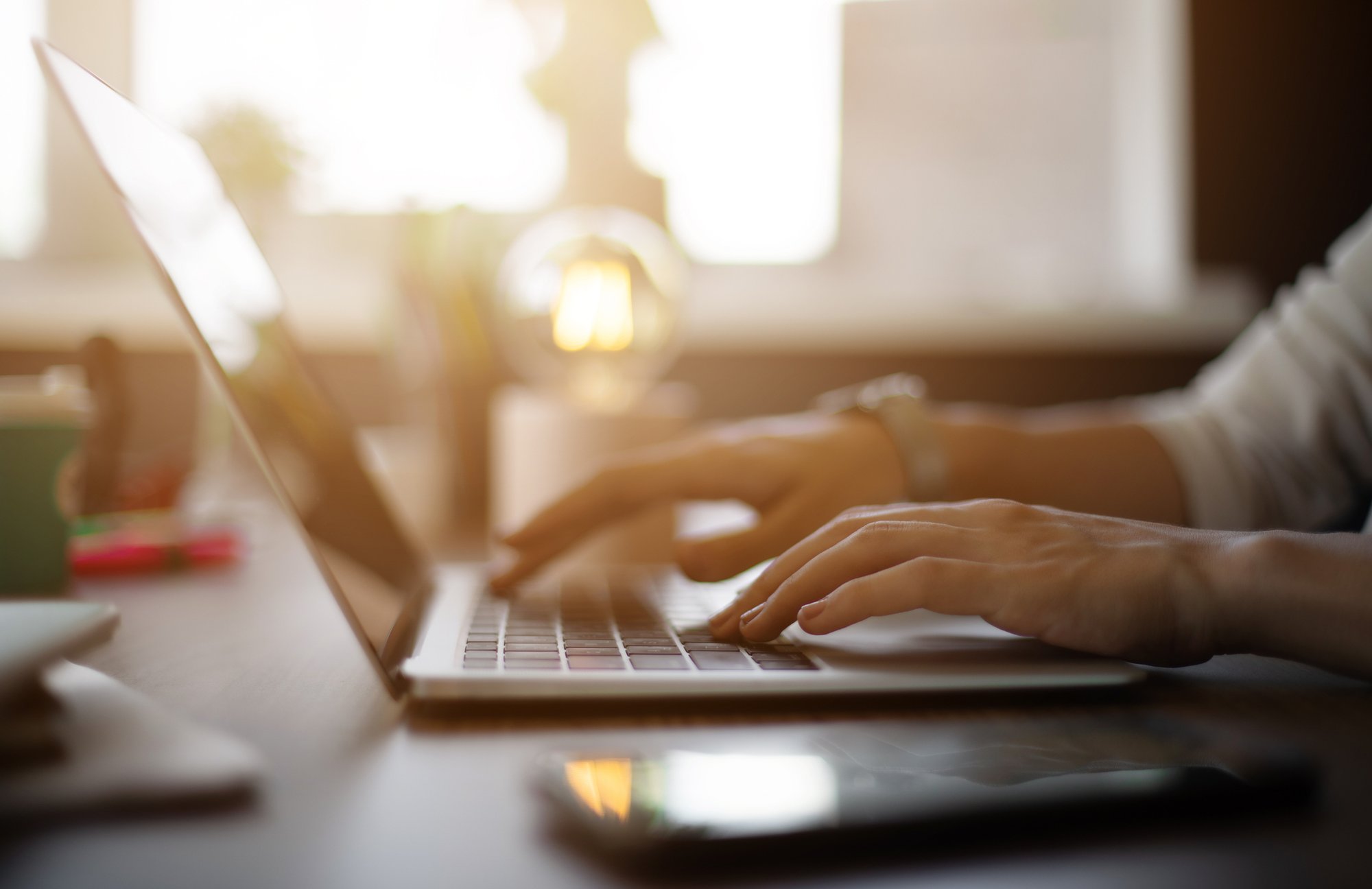 Close up of hands on laptop keys early in the morning