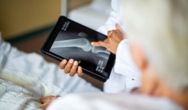 Doctor and patient reviewing knee X-ray on tablet