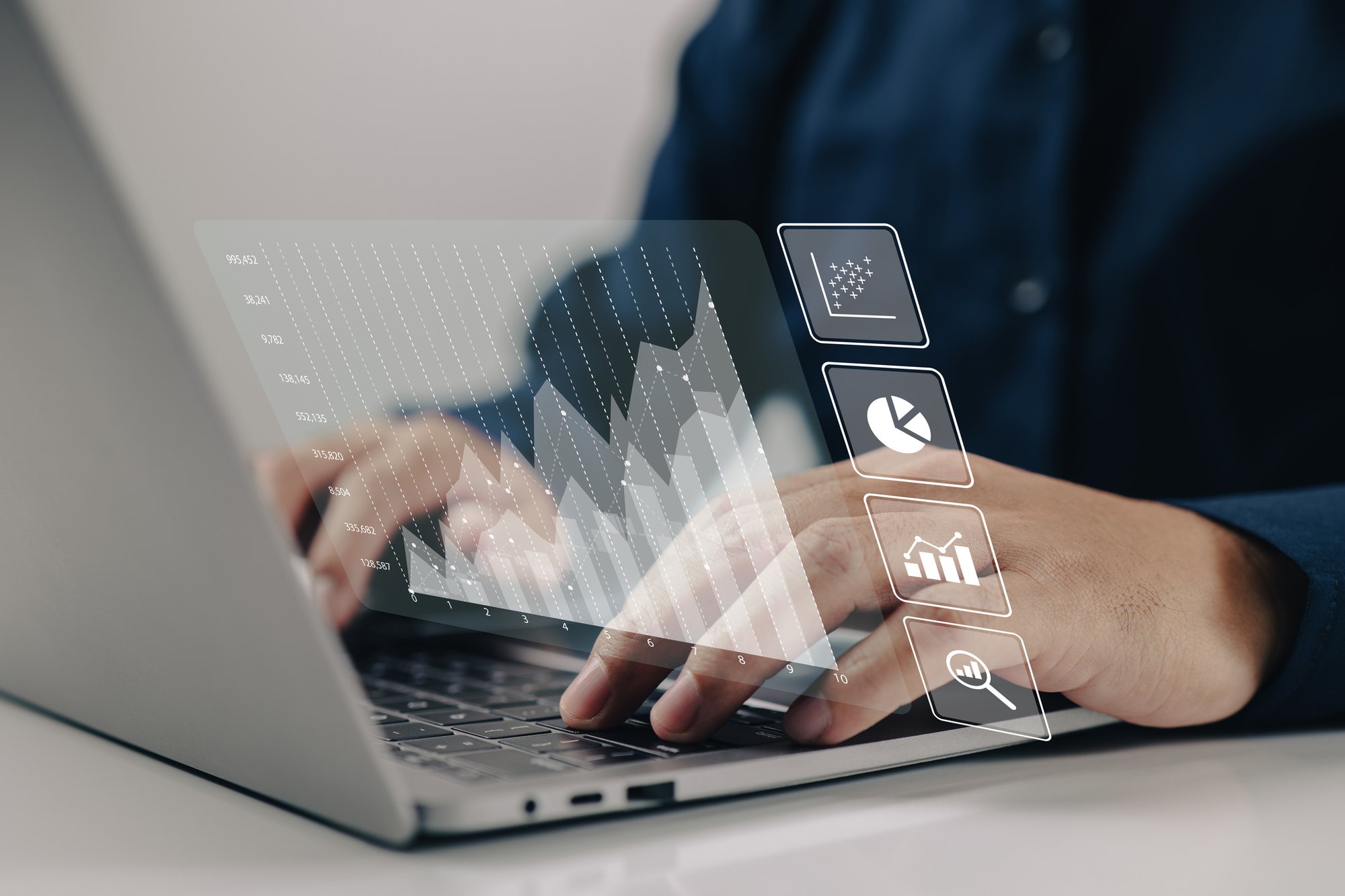 Close up of person's hands on laptop keyboard with hologram line, plot, bar, and pie charts