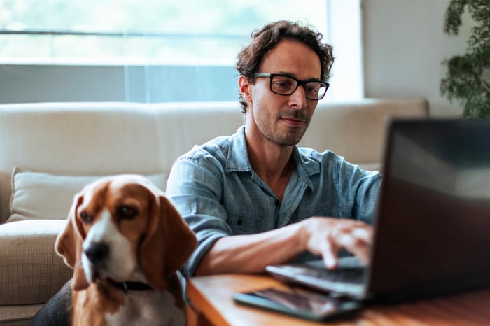 Man working on laptop next to beagle