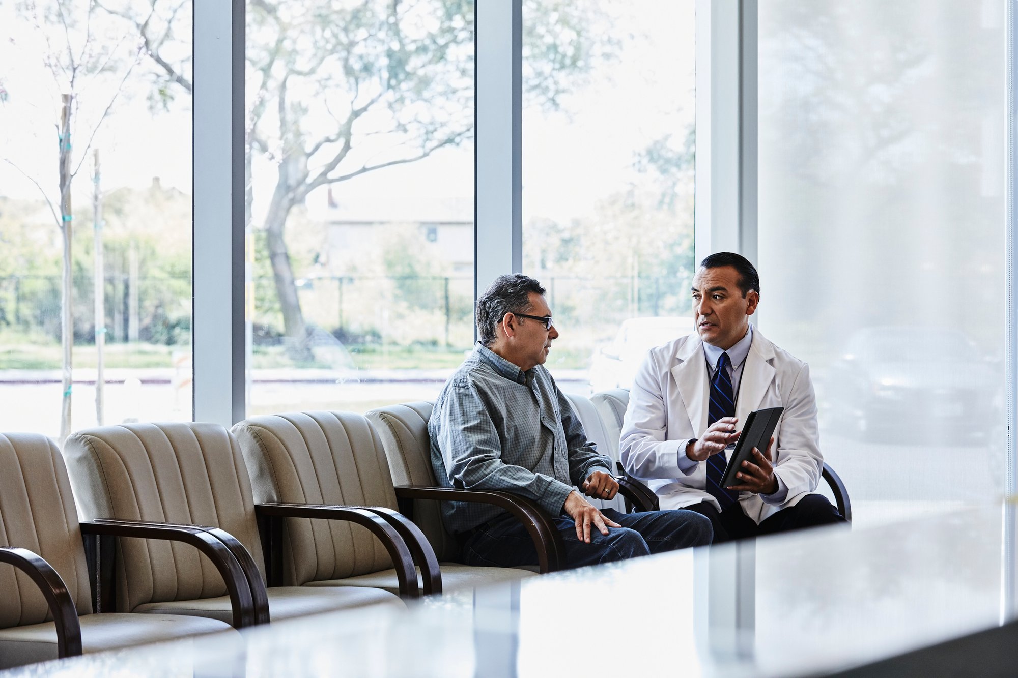 Patient meeting with doctor in large waiting room.