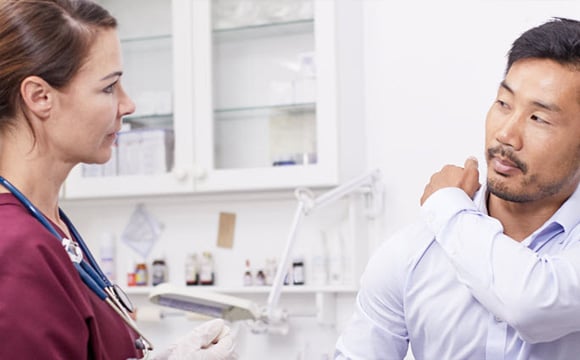 Patient visiting doctor, pointing at shoulder