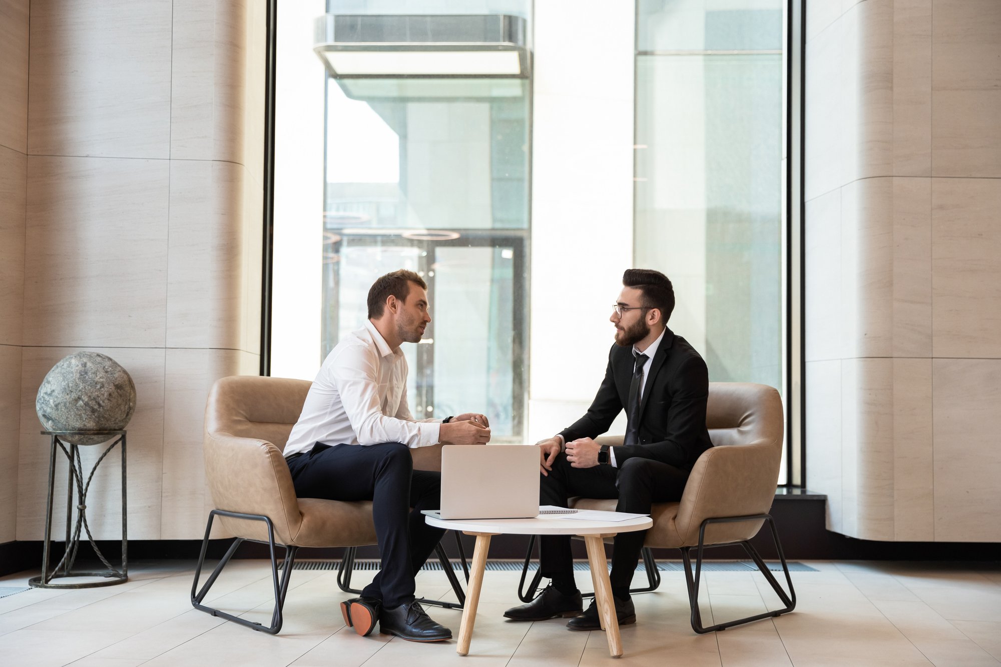 Two businessmen meeting in a modern office lobby