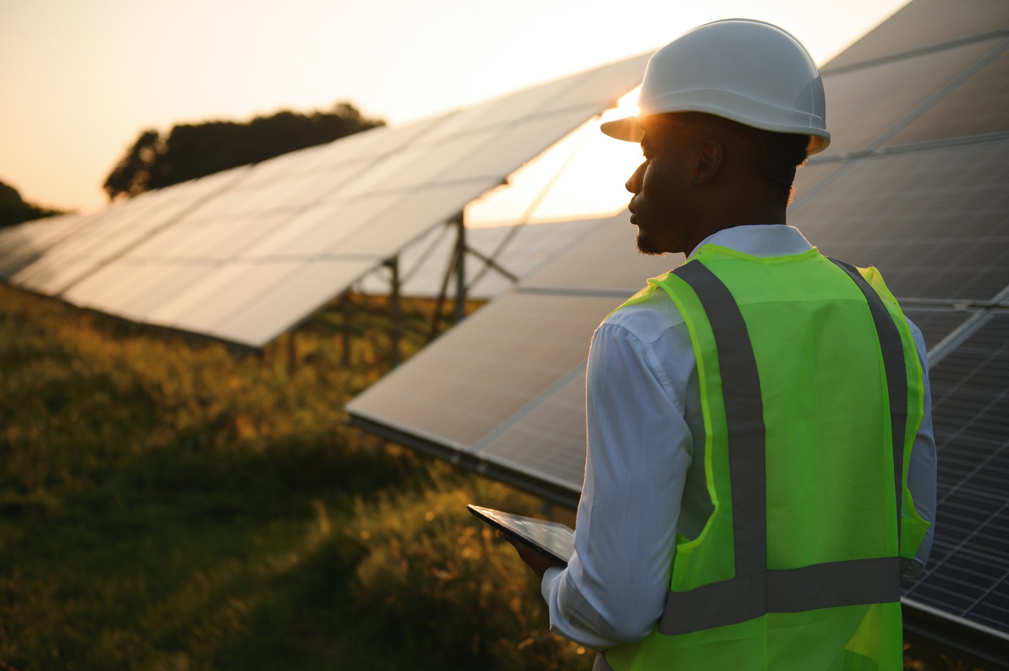 Worker inspecting solar panels at sunset